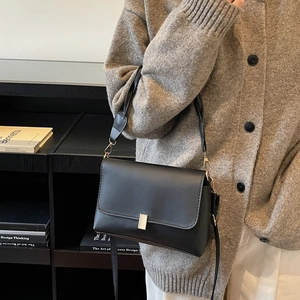 Minimalist black matte leather crossbody bag with elegant gold buckle shown on model