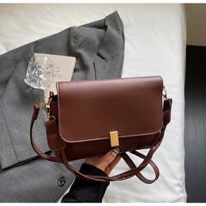 Detail shot of vintage brown leather handbag with gold buckle and adjustable strap
