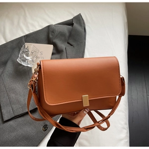 Detail of caramel brown PU leather bag with minimalist gold metal buckle and texture