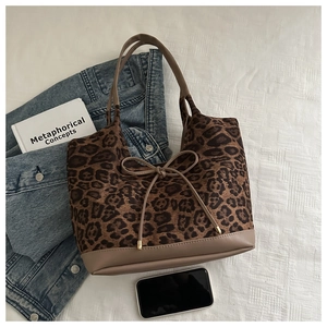 Detail of leopard print tote bag featuring a brown bow knot and premium leather handles