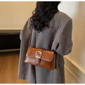 Detailed view of a vintage brown baguette bag with a silver buckle on a gray blazer
