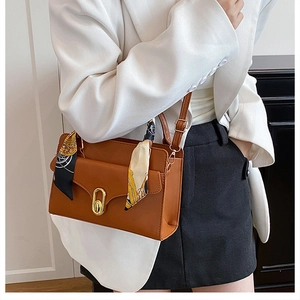 Detail of brown PU leather crossbody bag with elegant scarf wrap and gold twist lock