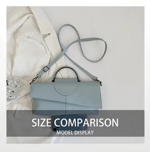 Detail of light blue crossbody bag with crocodile pattern flap and metal handle