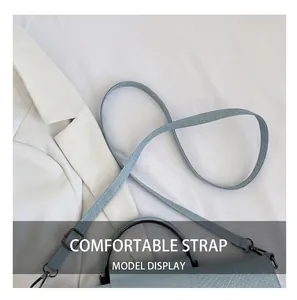 Detail of adjustable strap and embossed leather texture on light blue crossbody bag