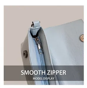Detail of light blue textured leather handbag with silver metal zipper and magnetic snap