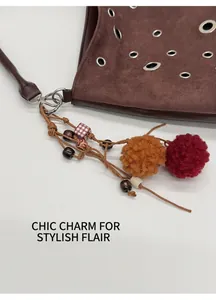 Detail of vintage brown suede tote bag with colorful faux fur ball and wooden bead charm