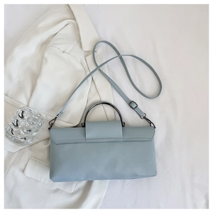 Macro detail of light blue handbag featuring faux snake skin texture and metal handle