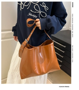 Close-up of caramel patent leather tote bag featuring retro silver metal eyelet straps