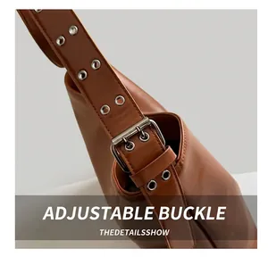 Detail of adjustable metal buckle and silver grommets on brown vintage oil wax leather bag