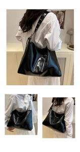 Detail of glossy black hobo bag with silver metallic eyelet hardware on the shoulder strap