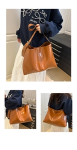 Close-up of caramel glossy hobo bag with wide shoulder strap and vintage metal buckle