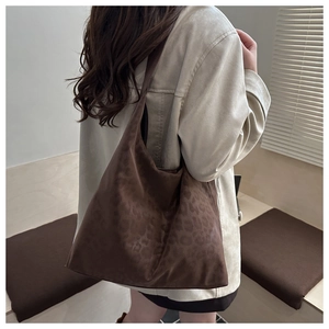 Close-up of a large dark brown suede tote bag with subtle leopard print embossing