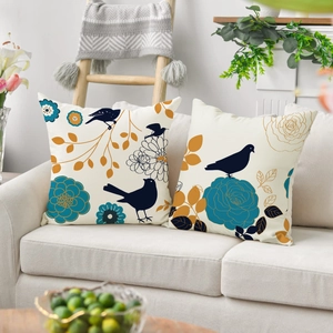 Close-up of two linen cushion covers with blue bird and floral prints on a sofa