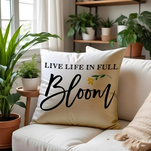 Linen floral pillow with Live Life In Full Bloom text on white sofa surrounded by plants