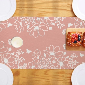 Detailed top view of a pink floral linen table runner with white flower patterns