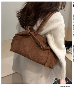 Detail of retro brown corduroy tote bag showing leather strap and metal buckle closure