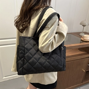 Black quilted tote bag with large capacity and shoulder straps shown on model