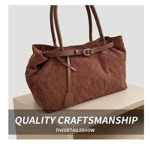 Close-up of brown corduroy tote bag showing leather strap and golden metal buckle details