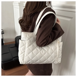 Close-up of white quilted tote bag featuring classic diamond stitching and metal zipper detail