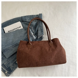 Close-up of brown corduroy tote bag texture with dark brown faux leather handle