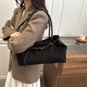 Chic black corduroy tote bag with slim leather straps worn by model in casual office style