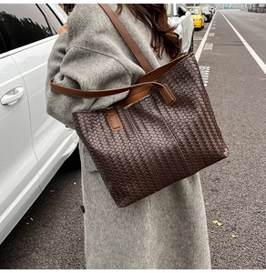 Detailed close-up of dark brown woven leather tote bag with elegant checkered pattern texture