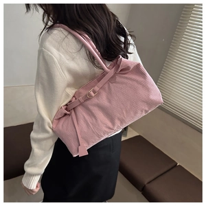 Detail of pink corduroy tote bag featuring golden hardware and soft ribbed texture
