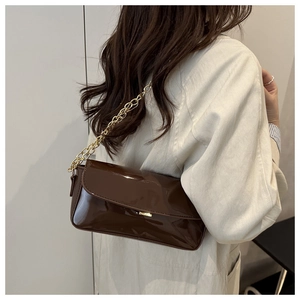 Detail view of glossy dark brown patent leather shoulder bag with a gold chain strap