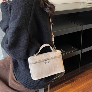Chic beige suede crossbody bag with heart zipper pulls shown in a lifestyle setting