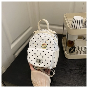 Detailed view of polka dot mini backpack featuring embroidery and silver chain strap