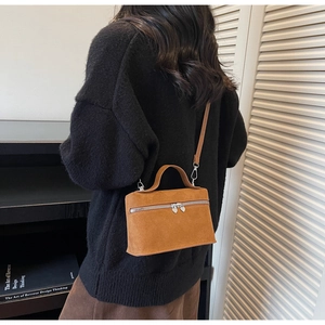 Detail view of brown suede vanity bag featuring heart-shaped metal zipper pulls on a crossbody