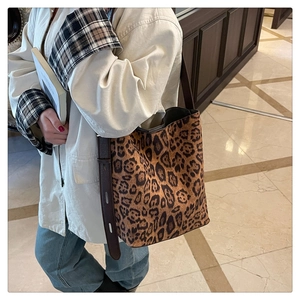 Detail of leopard print bucket bag featuring an adjustable brown leather strap and buckle