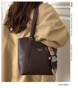 Detail of dark brown leather tote bag with brand logo and cute rabbit charm pendant