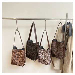 Row of leopard print suede tote bags in various colors hanging on a display rack