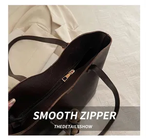 Detail of smooth gold zipper and dark brown leather texture on a vintage tote bag