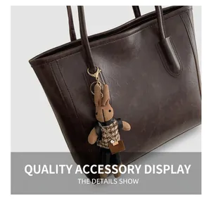 Detail of a brown knitted bunny charm with houndstooth outfit on a leather tote bag