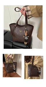 Detail of dark brown leather tote bag showing gold logo and knitted rabbit charm