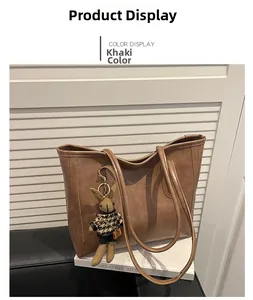 Detail view of large khaki tote bag with a plaid rabbit charm on a leather base