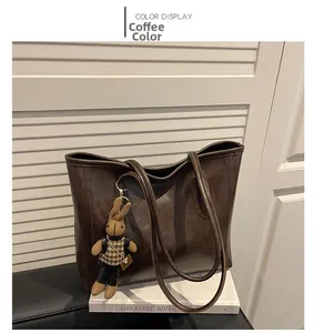 Detail of coffee brown tote bag with smooth texture and cute rabbit charm pendant