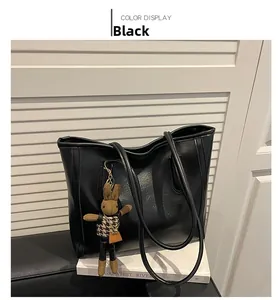 Detail of black tote bag with micro-gloss leather texture and a plush rabbit pendant