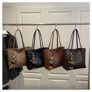 Detail view of large leather tote bags in four colors with cute bunny charms on a rack