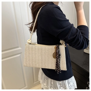 Dettaglio di una borsa a tracolla intrecciata beige con cinturino in pelle e nappa a chiave
