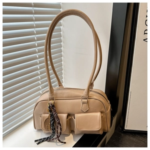 Détail du sac à main en cuir souple abricot avec doubles poches à rabat et charme tressé