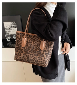 Close-up of leopard print tote bag with brown handles styled with a black cardigan