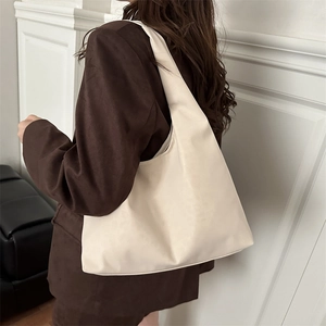 Minimalist cream white PU leather tote bag with wide shoulder strap on brown blazer