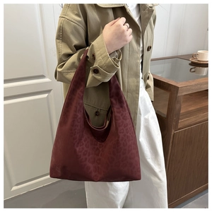 Close-up of a burgundy leopard print tote bag styled with a khaki trench coat