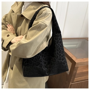Detail of a vintage leopard print hobo tote bag worn with a beige trench coat