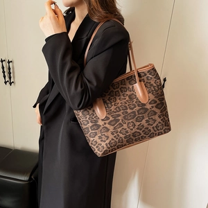 Chic leopard print tote bag with brown leather straps shown on a stylish model