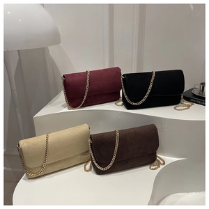 Detail of four matte suede chain bags in burgundy, black, beige, and brown on white steps
