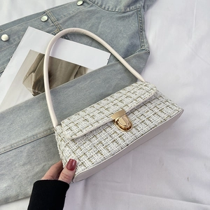 Close-up of white woven tweed baguette bag with gold twist lock and elegant texture